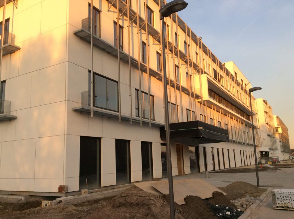Gevel van het nieuwe ziekenhuis in aanbouw in de provincie Antwerpen in laag zonlicht
