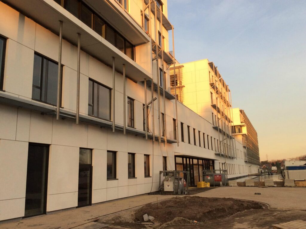Lange gevel van het ziekenhuis in aanbouw met brandstoftanks in stalen frames bij een ingang