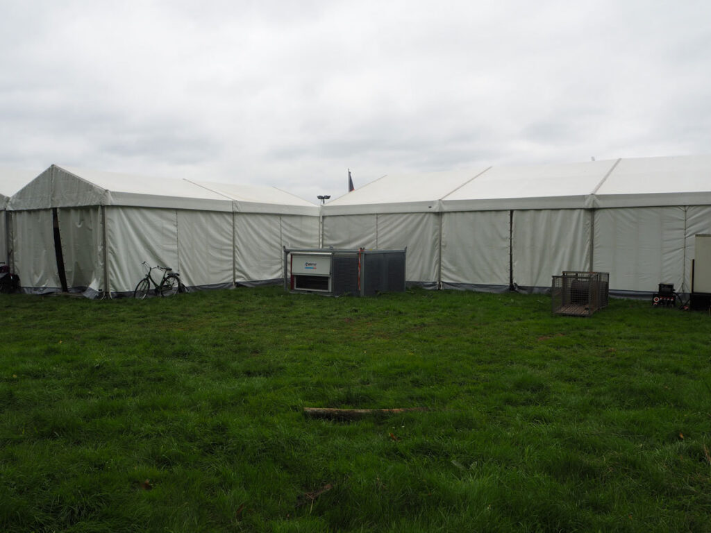 Grasveld met grote witte tenten op Pukkelpop 2017 en een mobiel aircotoestel in een kooi