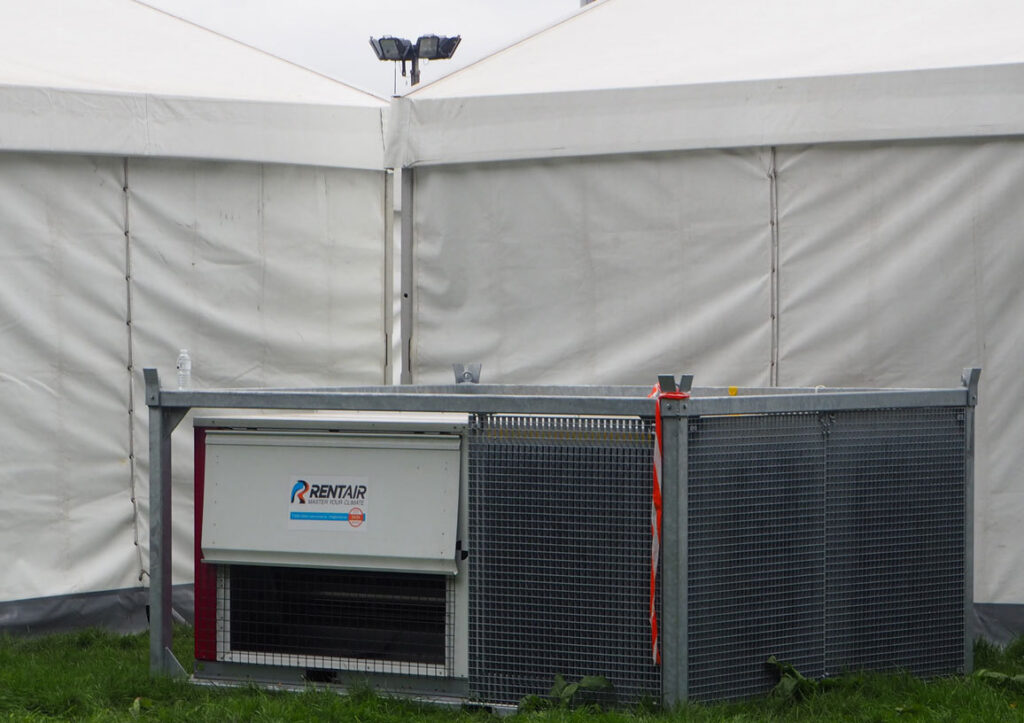 Mobiel aircotoestel van Rentair in een metalen kooi tegen een witte festivaltent