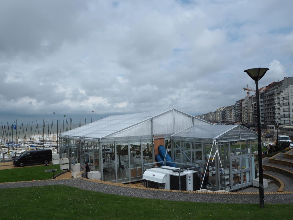 Doorschijnende tentconstructie van de vlindertuin met rooftop unit, zeilboten en appartementen in Knokke