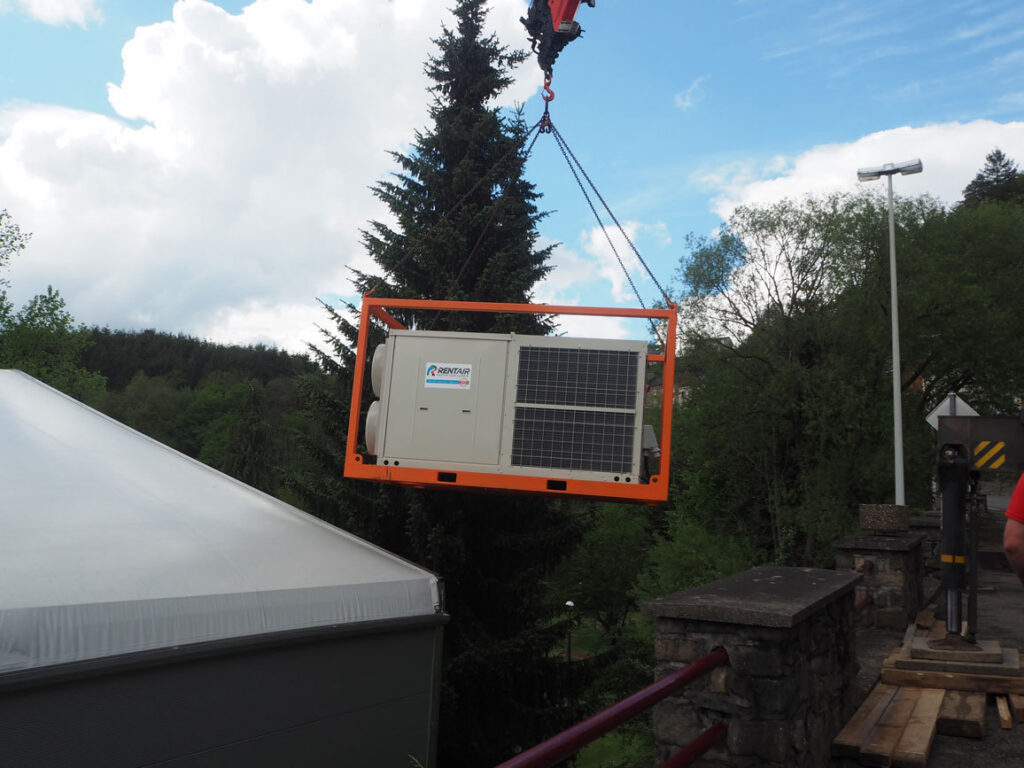 Rooftop warmtepomp van 70 kW hangt aan een kraan naast de tijdelijke supermarkt