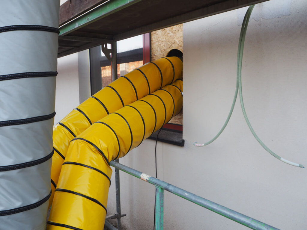 Gele luchtslangen die langs de stelling via een afgedichte raamopening het studentengebouw ingaan
