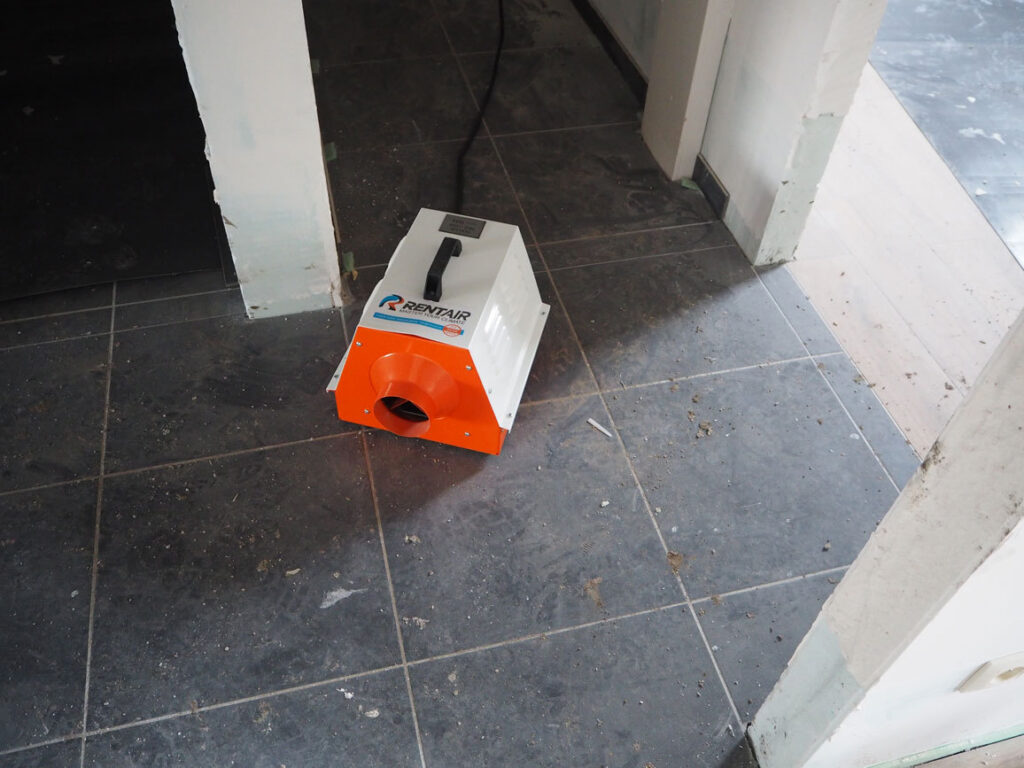 Oranje elektrisch verwarmingstoestel van Rentair op een donkere tegelvloer, van bovenaf gezien