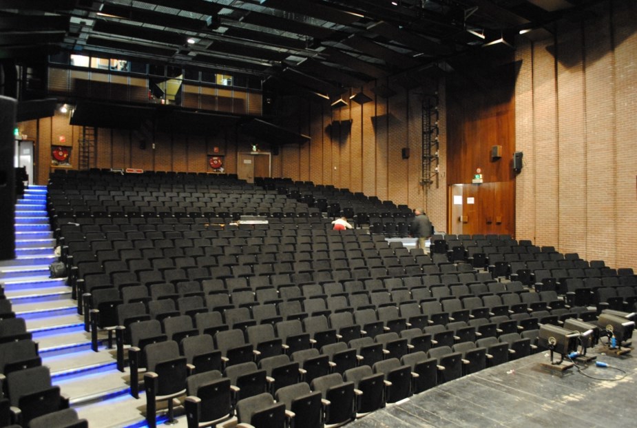 Theaterzaal met rijen zwarte zitjes voor een dansvoorstelling in Tubeke, gekoeld door een airco-warmtepomp
