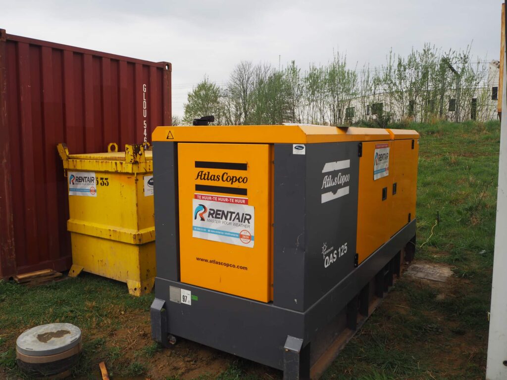 Generator Atlas Copco QAS 125 met Rentair-logo en gele olietank op een bouwwerf in Vorst